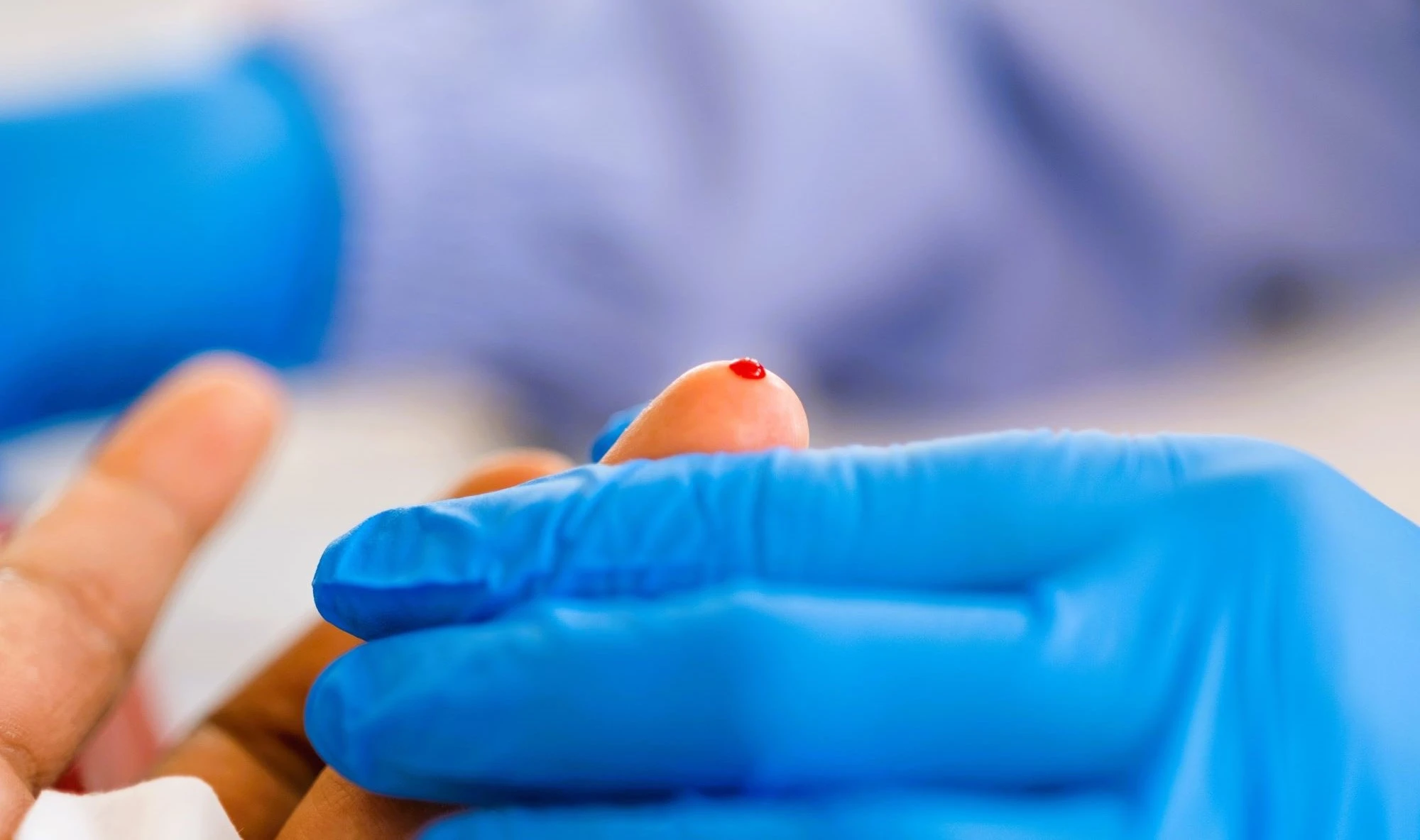 Photo of a person sampling a drop of blood from a finger prick Room