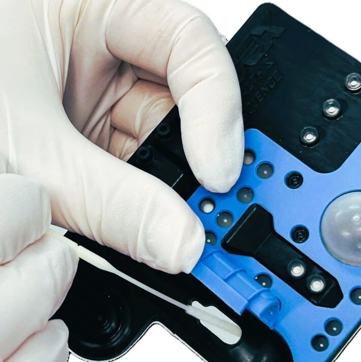 Photo of a Microfluidic POC Cartrige. A person is inserting a sample .